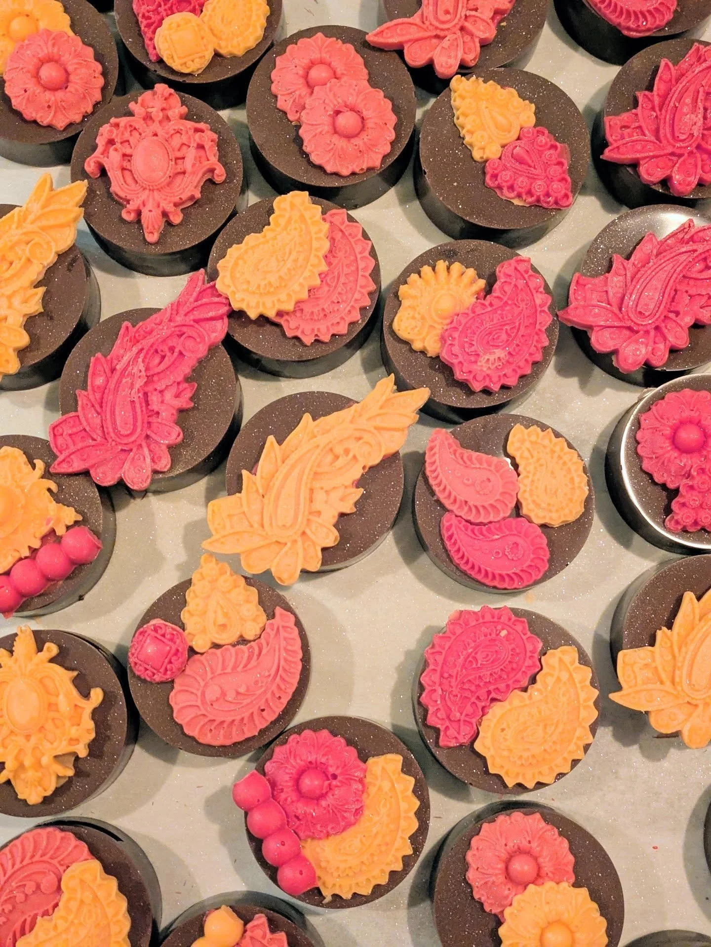Ornate paisley and mehndi-patterned chocolate favors in magenta and saffron — AMR Catering's American–Indian fusion signature.