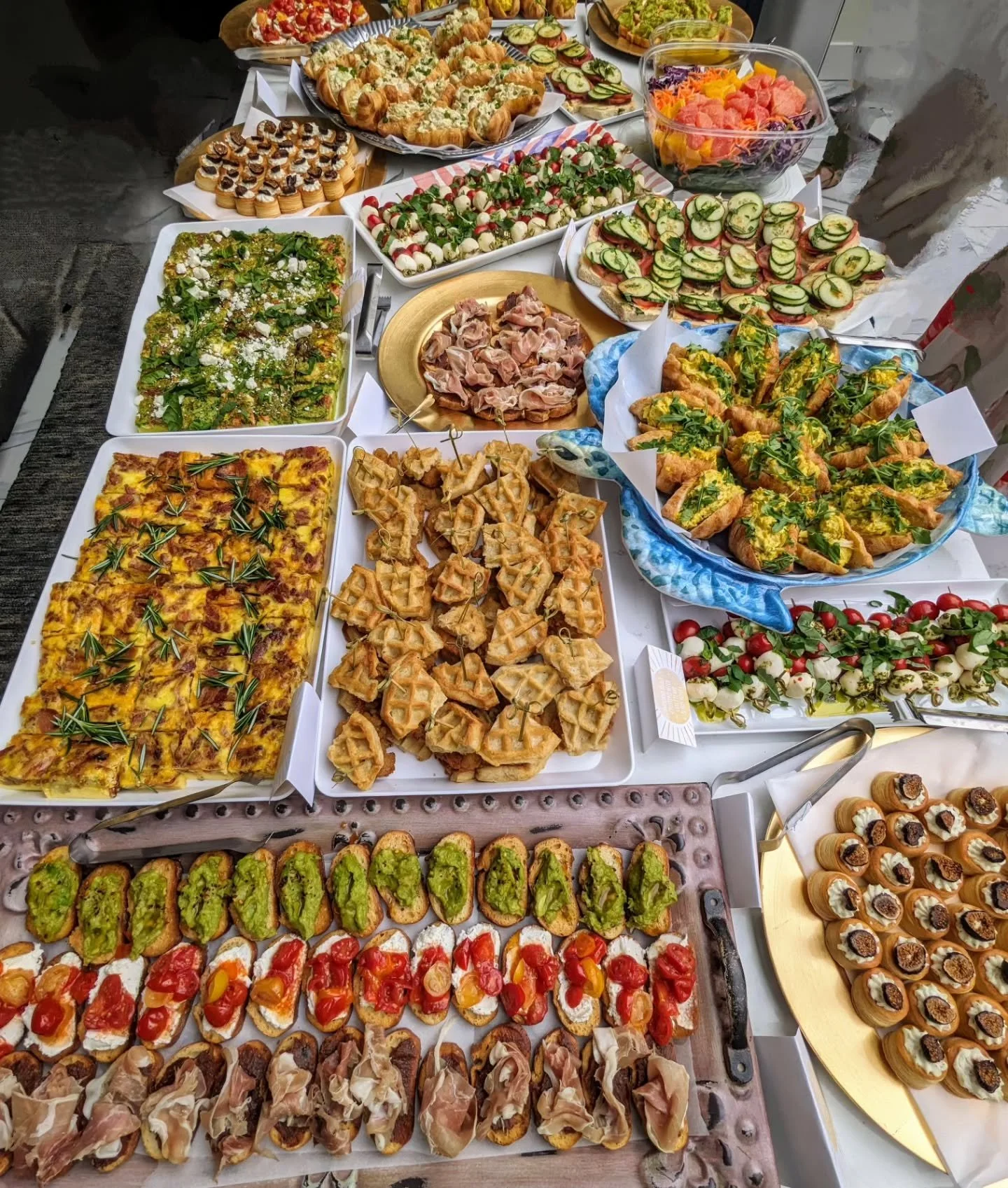 An overhead AMR Catering grazing table layered with bruschetta, caprese, frittata and prosciutto, glowing against a dark backdrop.
